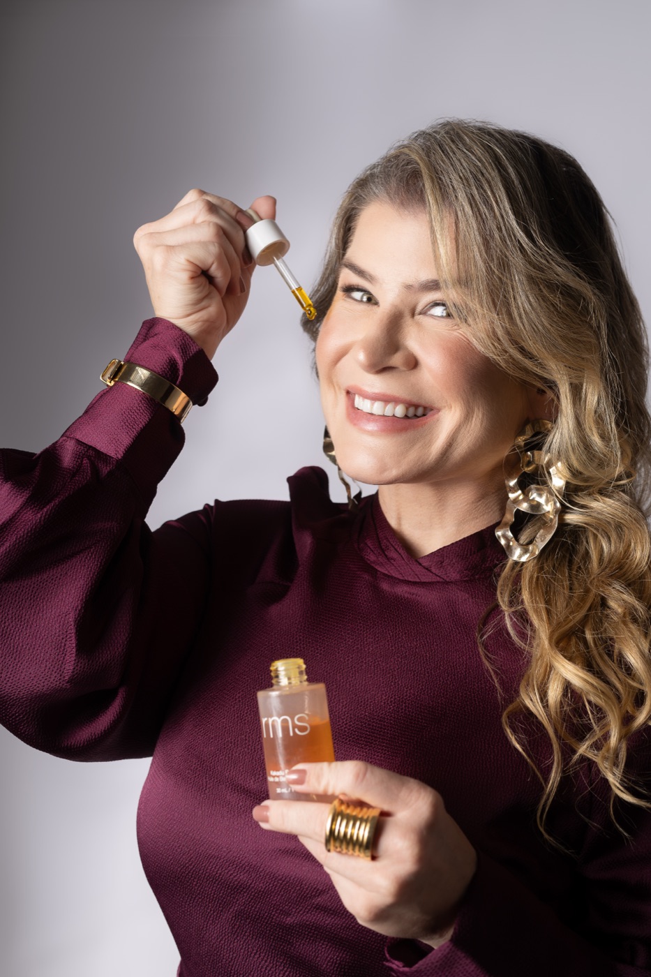 Dra. Bianca aplicando sérum com conta-gotas, frasco de clean beauty na mão
